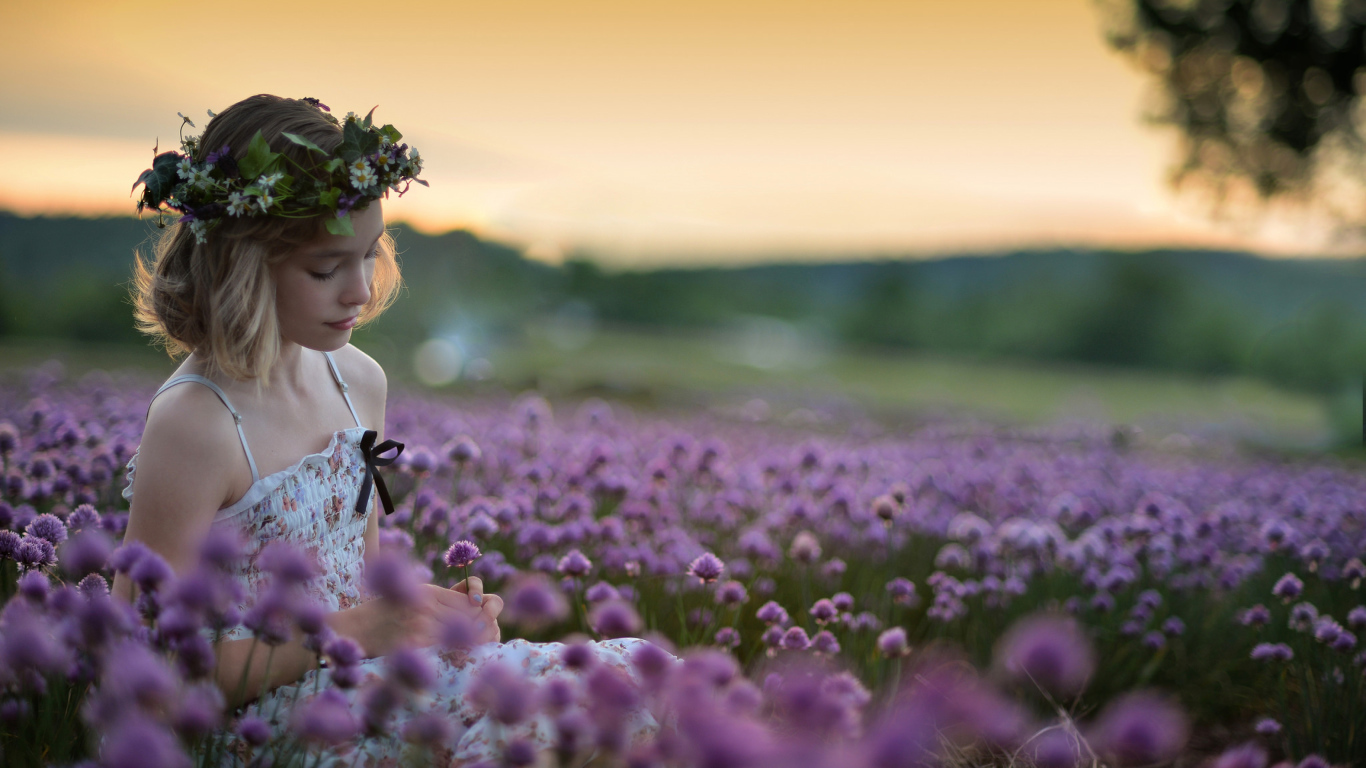 Нежная маленькая девочка сидит на поле с сиреневыми цветами