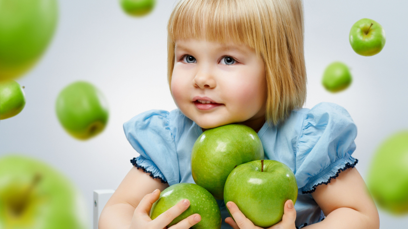 Маленькая девочка блондинка с зелеными яблоками