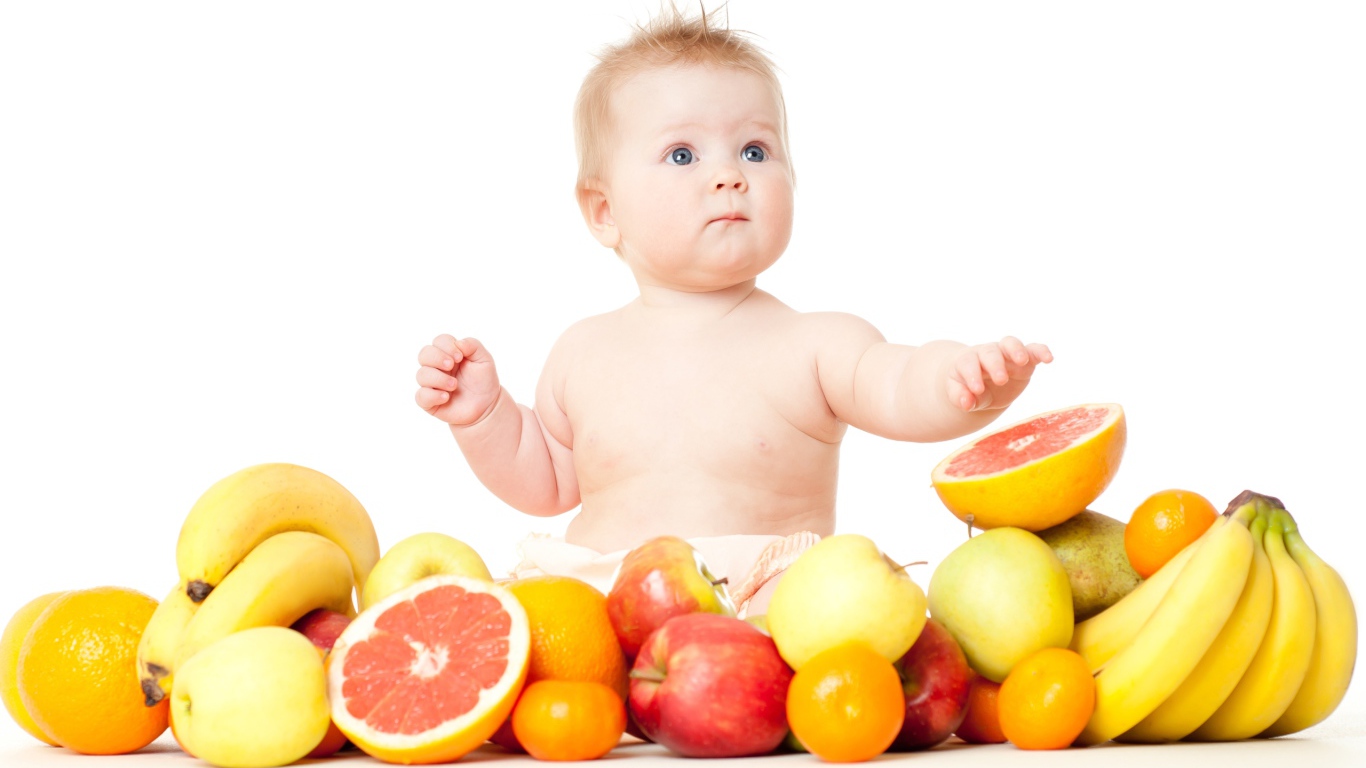 Маленький голубоглазый ребенок с фруктами на белом фоне