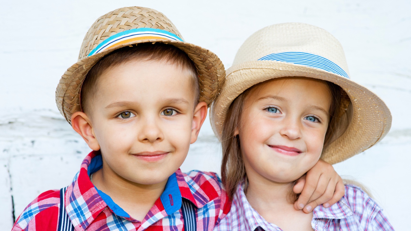 Маленькие мальчик и девочка в соломенных шляпах на пляже