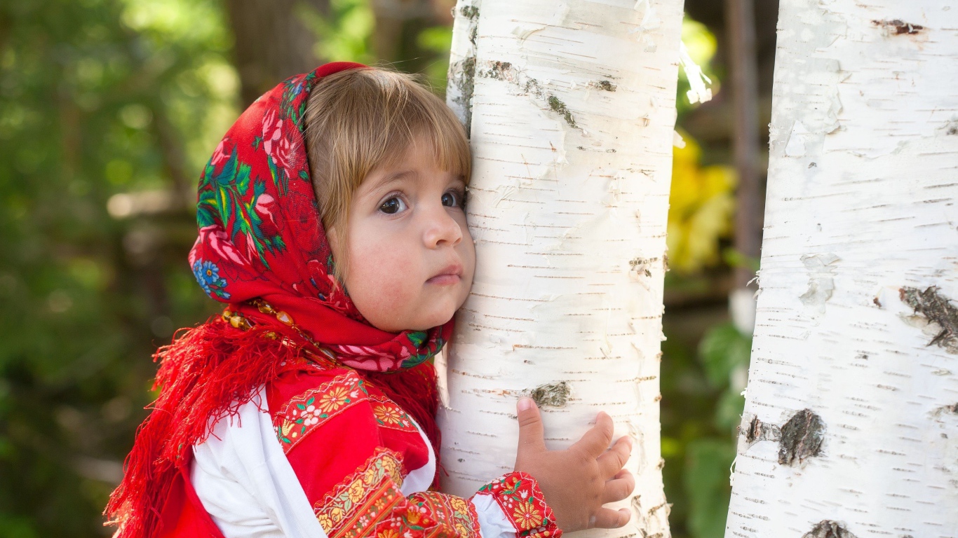 Маленькая девочка в красном платке обнимает березу