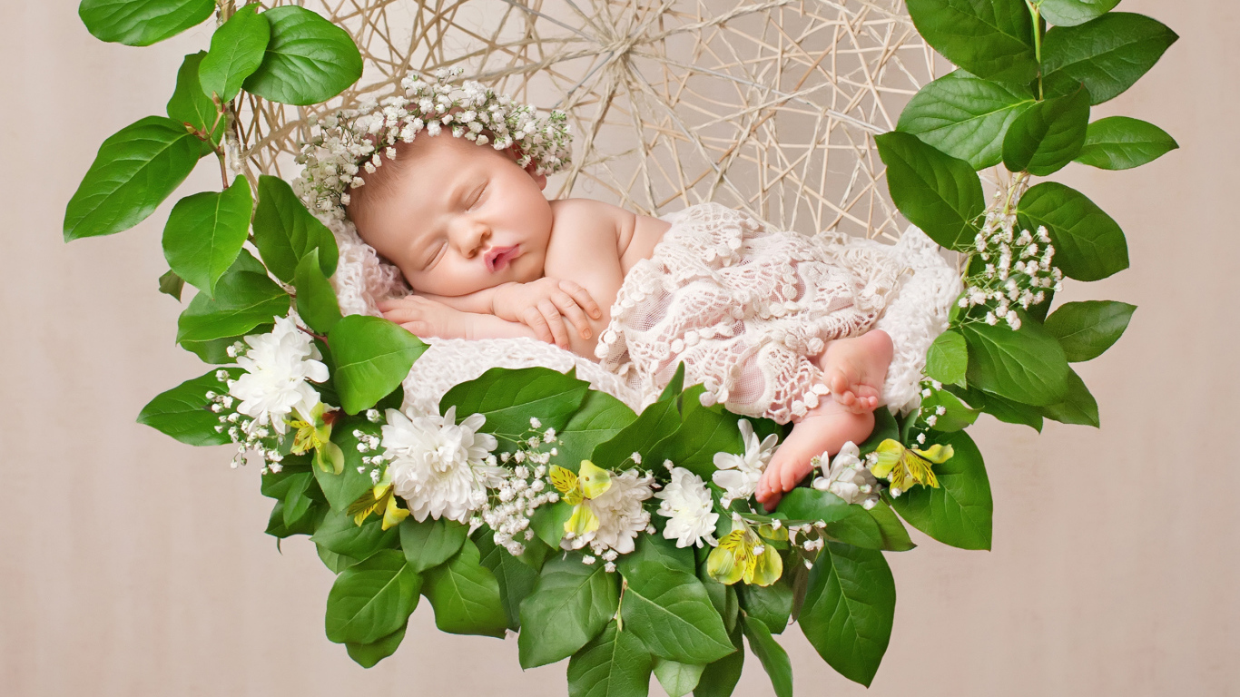 Маленькая девочка спит в колыбеле украшенной зелеными листьями