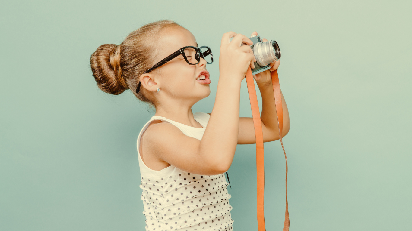 Маленькая девочка в очках с фотоаппаратом
