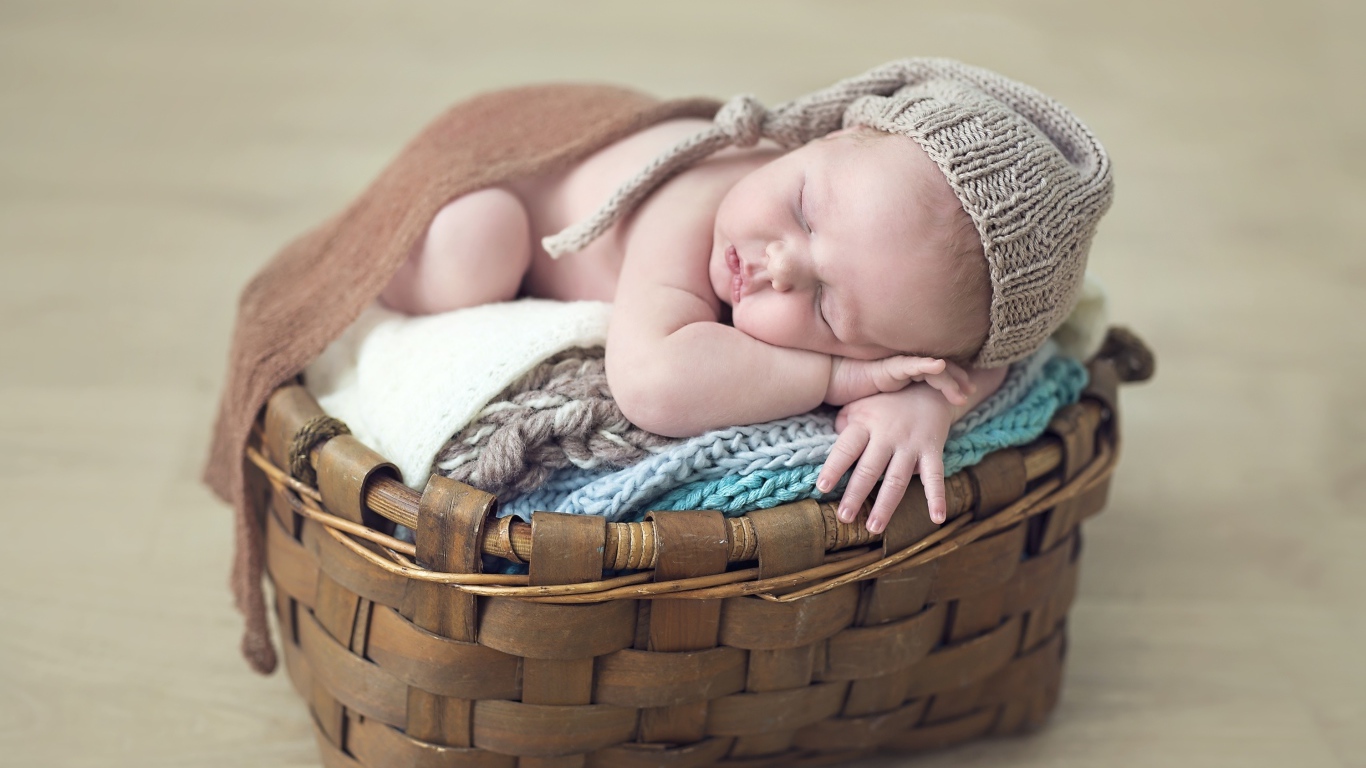 Спящий грудной ребенок в шапке в корзине 