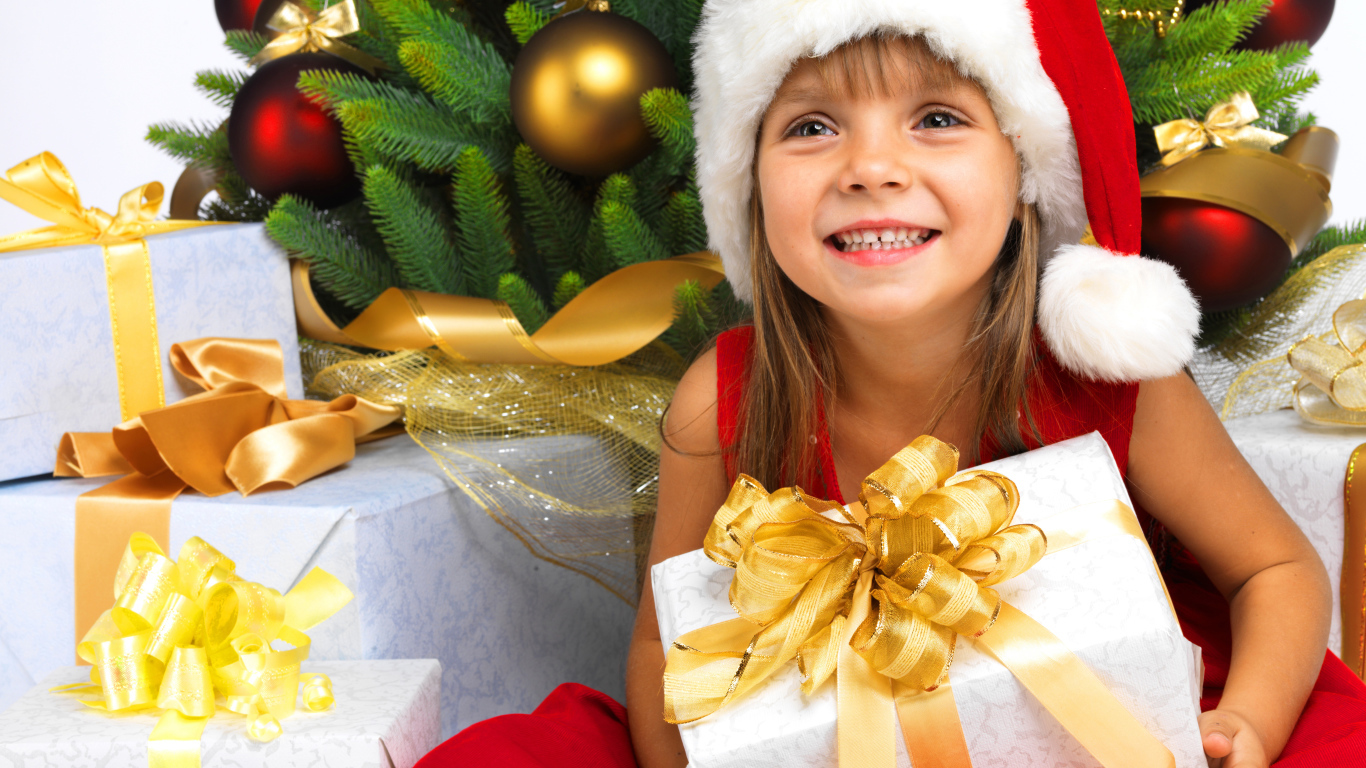 Улыбающаяся девочка в новогоднем костюме с подарками под елкой