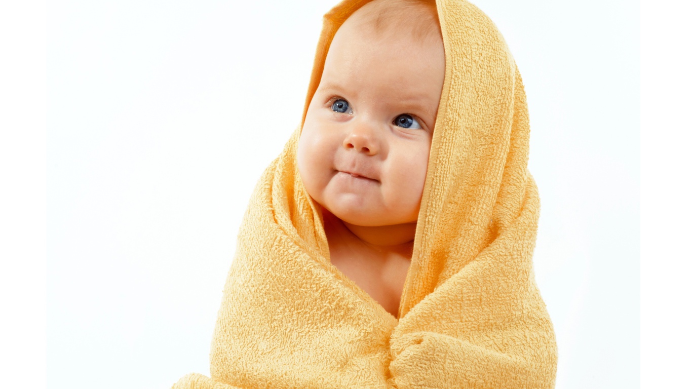 Грудной ребенок в желтом полотенце на белом фоне