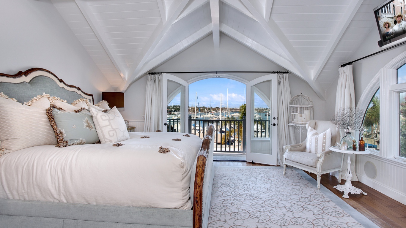 Белая спальня с большой высокой кроватью и балконом 