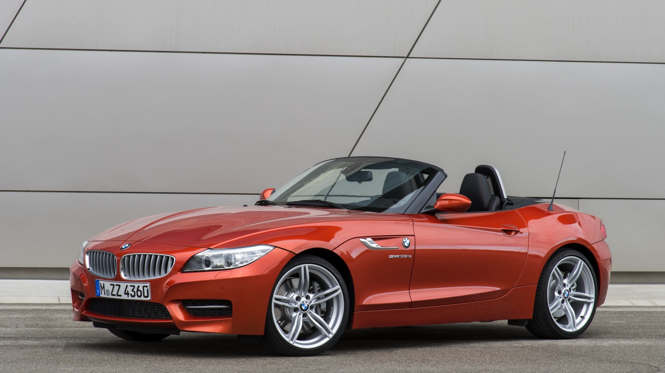 Оранжевый автомобиль кабриолет BMW Z4 на фоне стены