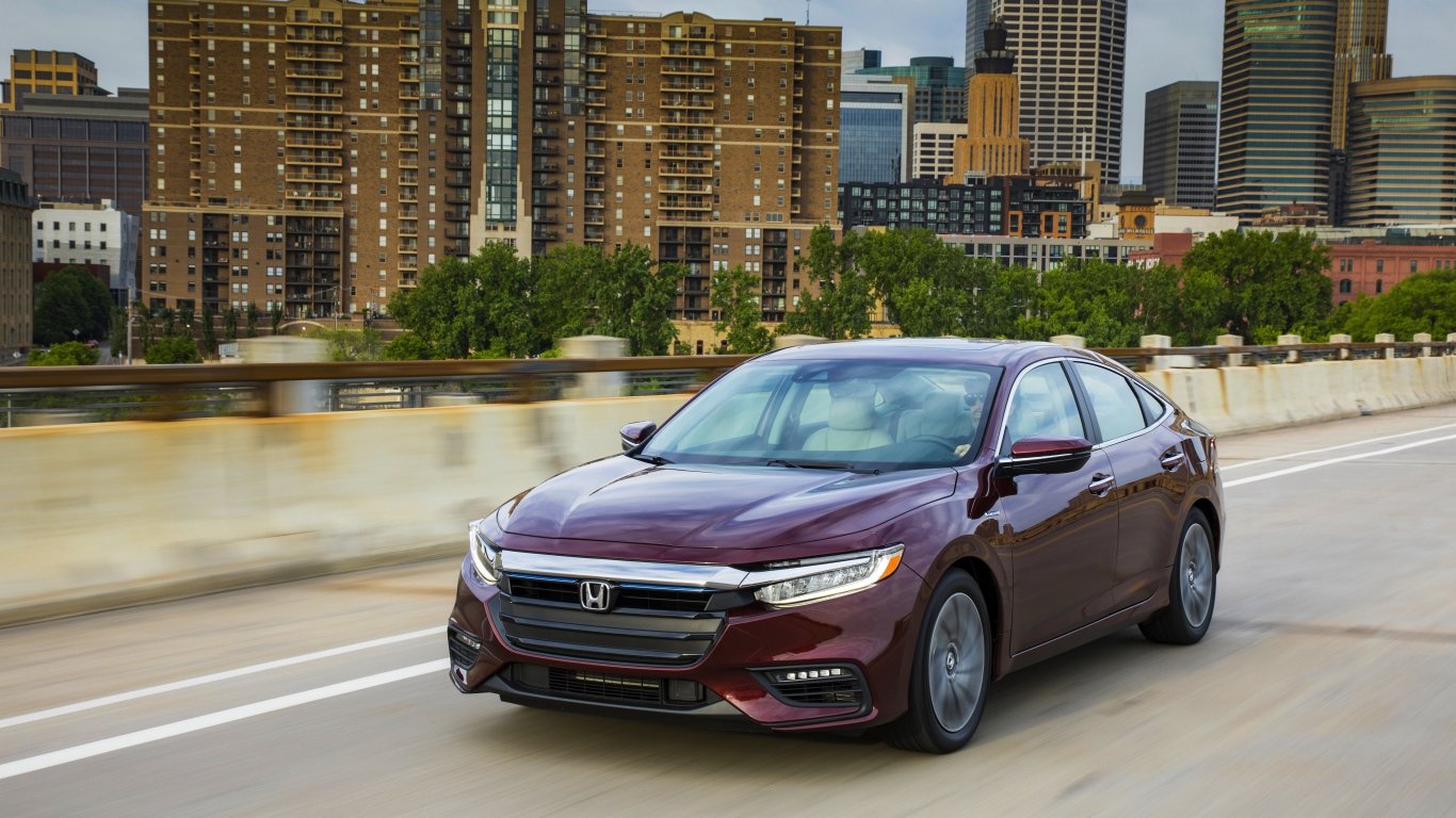 Бордовый автомобиль Honda Insight на фоне города