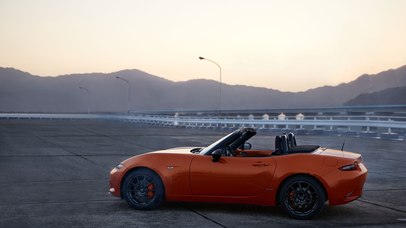 Оранжевый автомобиль кабриолет Mazda MX-5 на фоне неба
