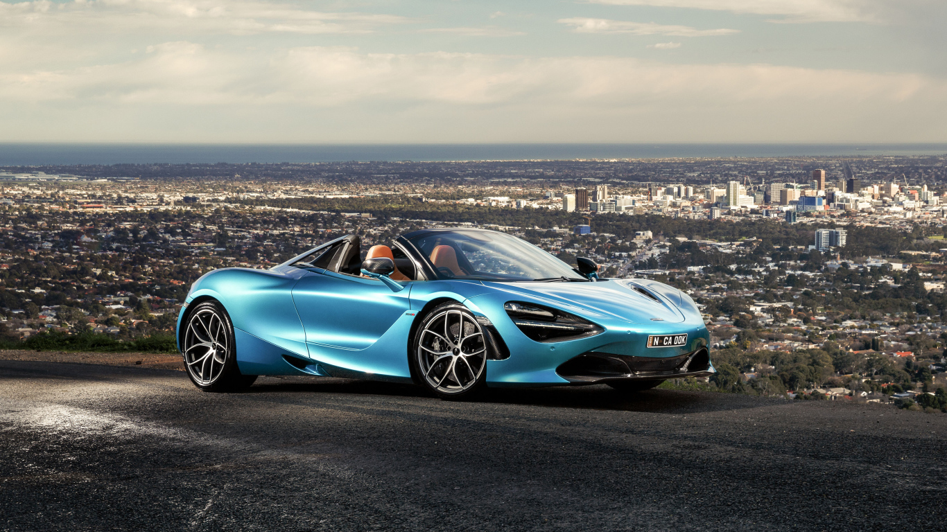 Голубой спортивный автомобиль McLaren 720S Spider 2019 года на фоне города
