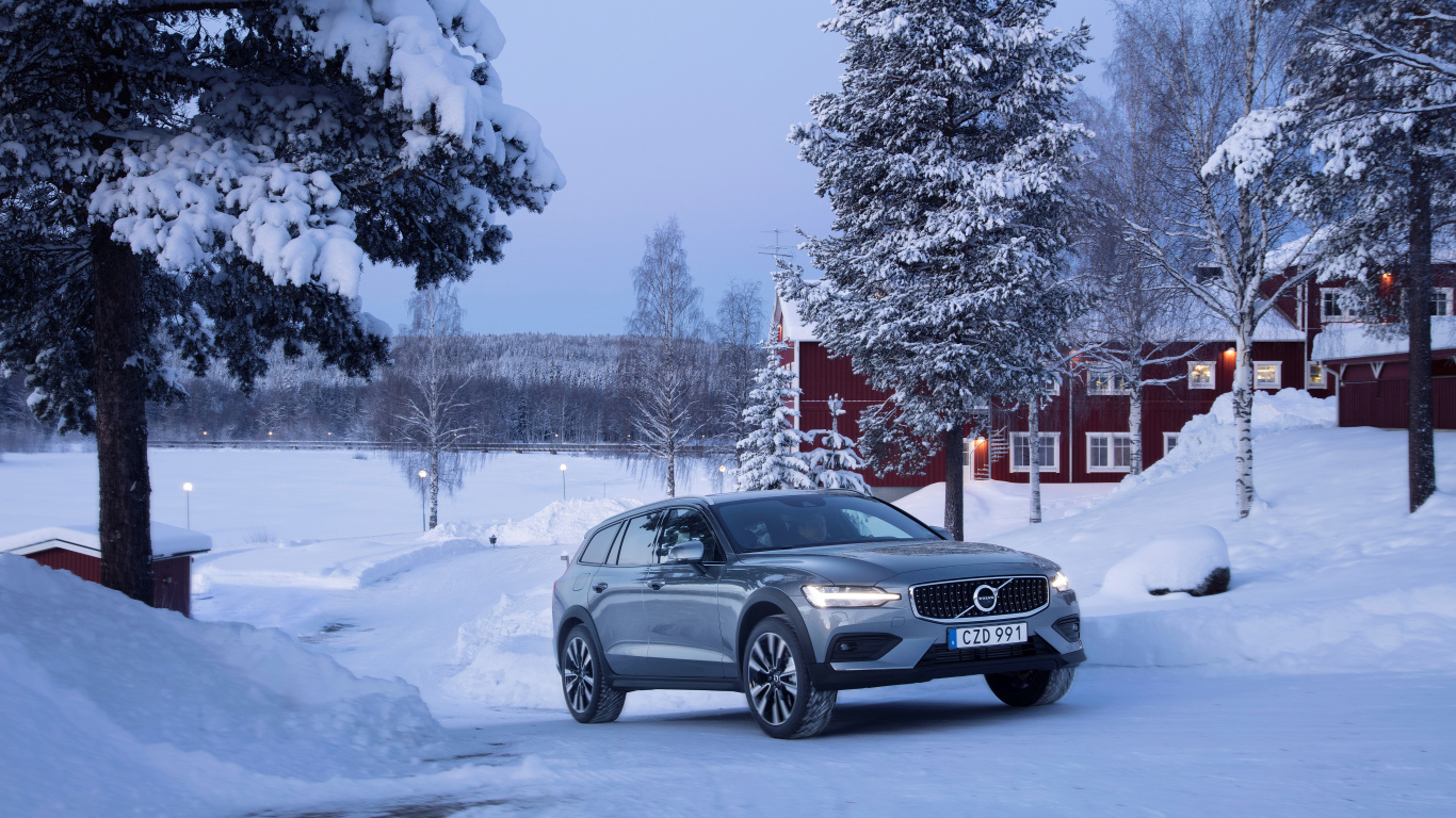 Автомобиль Volvo V60 на фоне заснеженных деревьев 