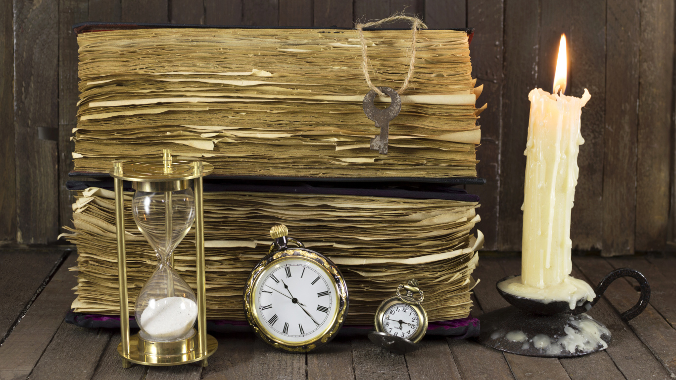 Старинные книги, зажженная свеча, ключи и часы на столе