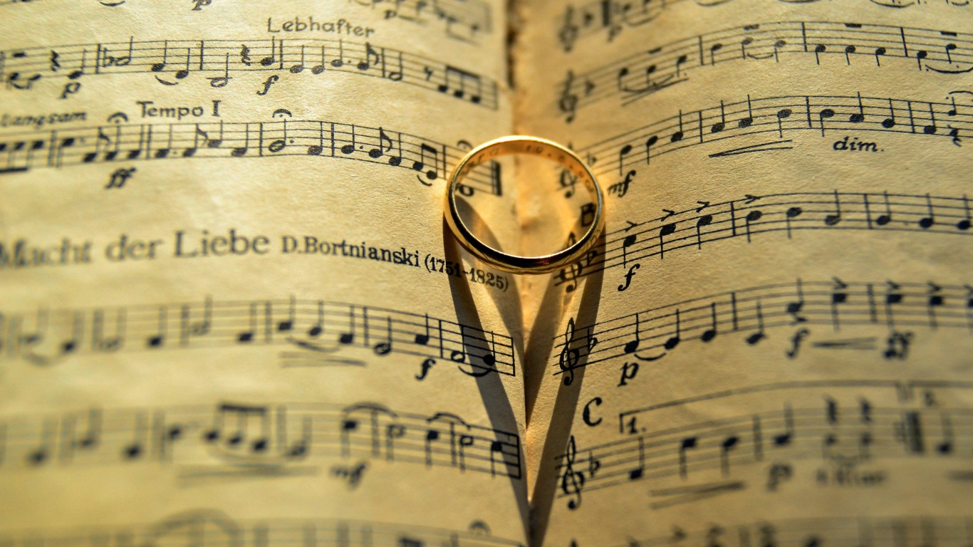 Золотое обручальное кольцо лежит на нотной тетради