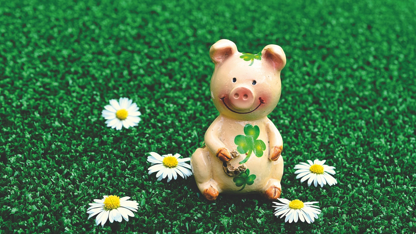 Статуэтка поросенка на зеленой траве с ромашками