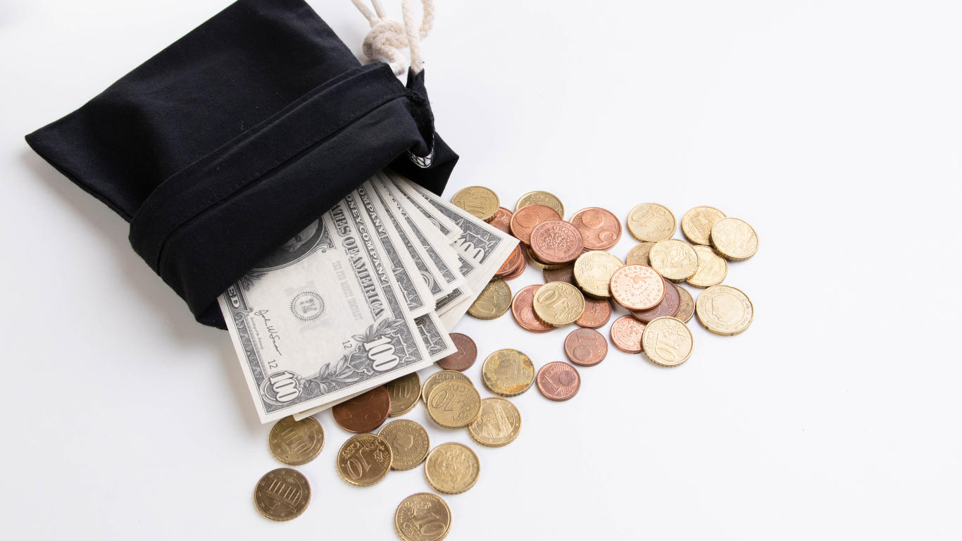 Кошелек с монетами и долларами на белом фоне