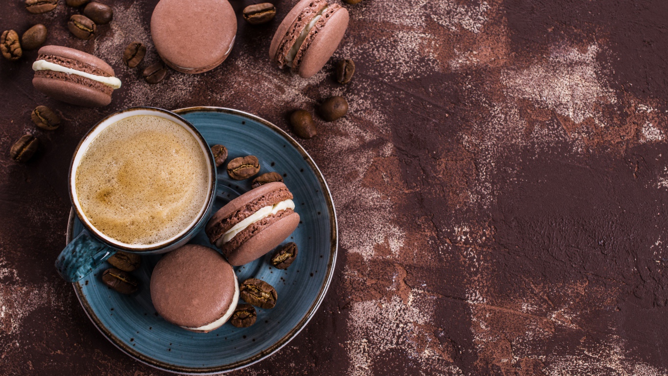 Чашка кофе с шоколадными макарунами на столе