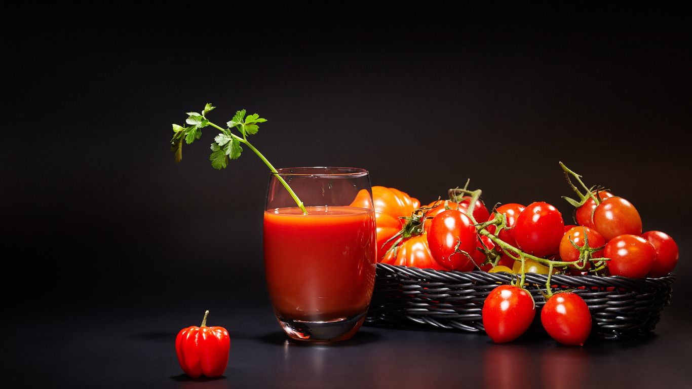 Стакан томатного сока на столе с помидорами