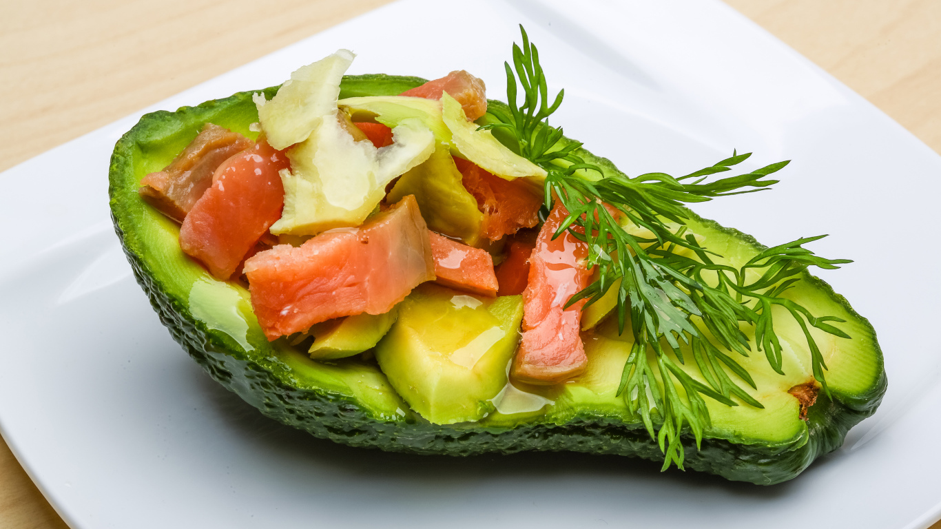 Авокадо с салатом из красной рыбы на белой тарелке