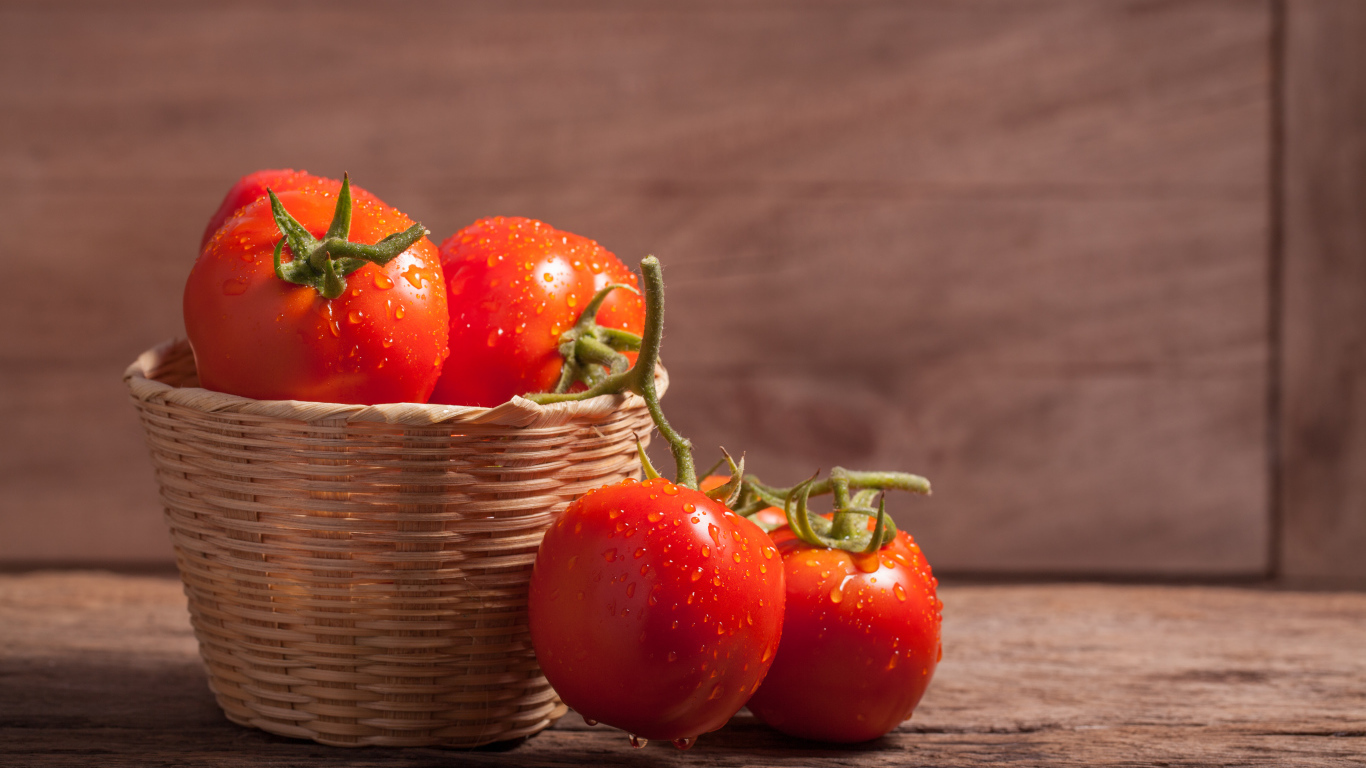Красивые красные мокрые помидоры в корзине на столе 