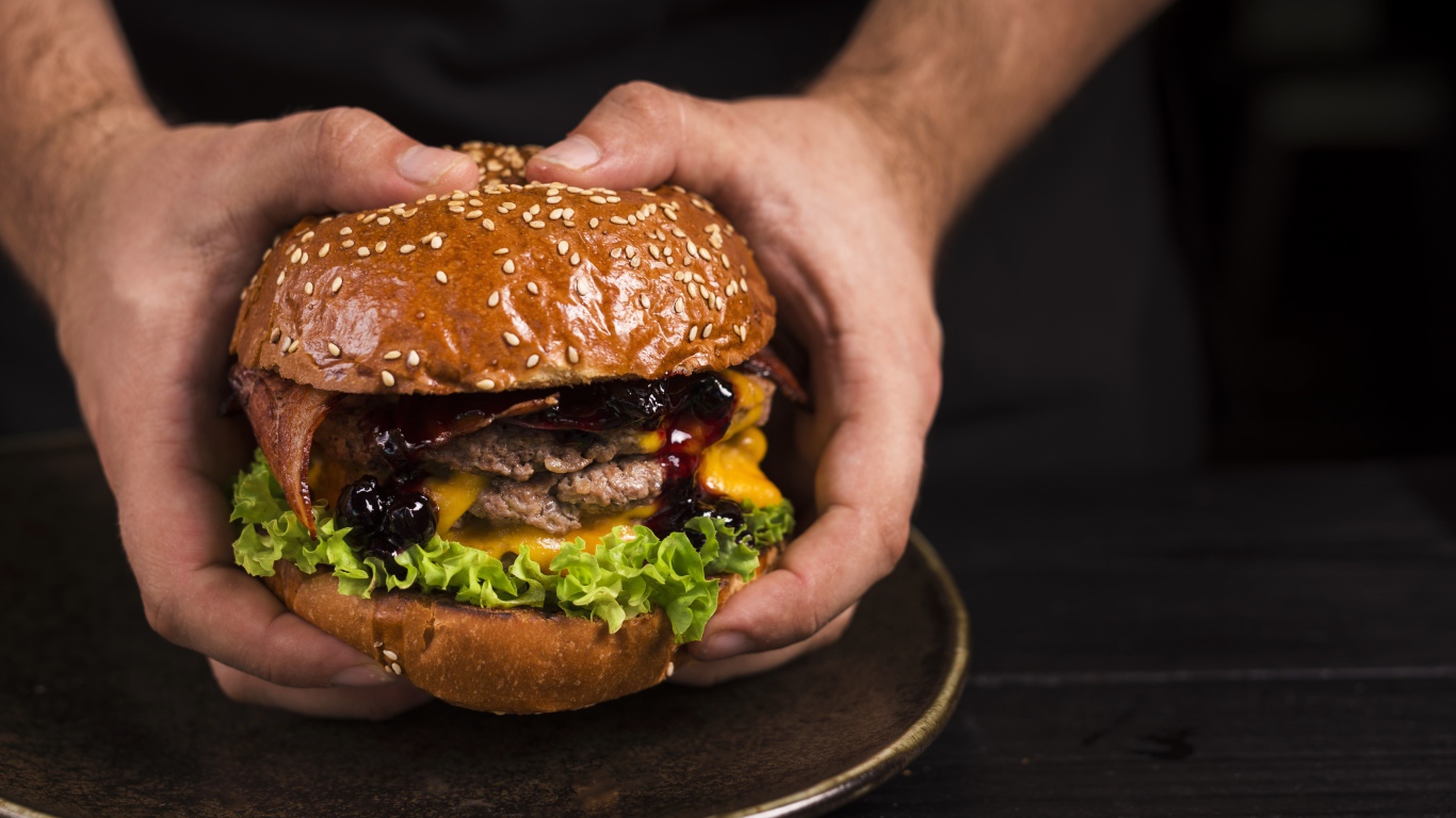 Большой сочный гамбургер в руках