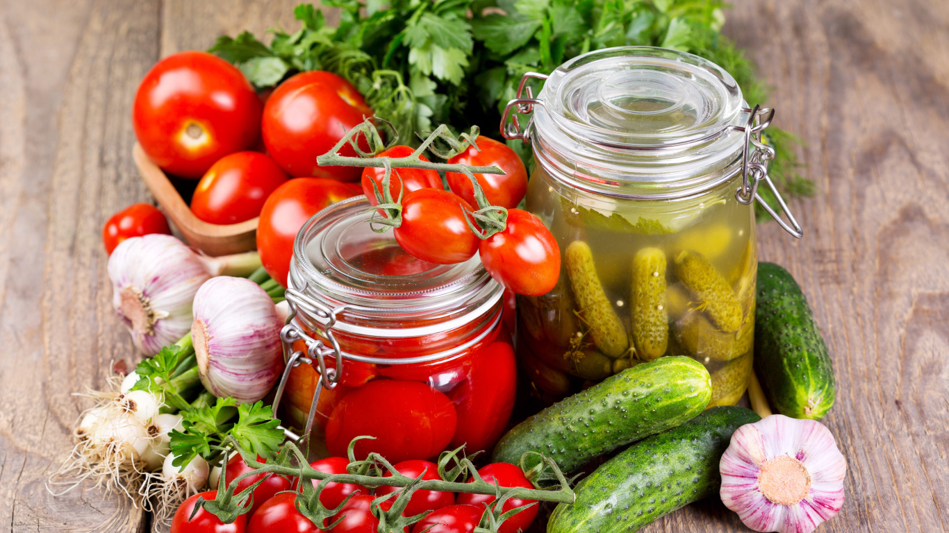 Консервированные помидоры и огурцы на столе со свежими овощами и зеленью 