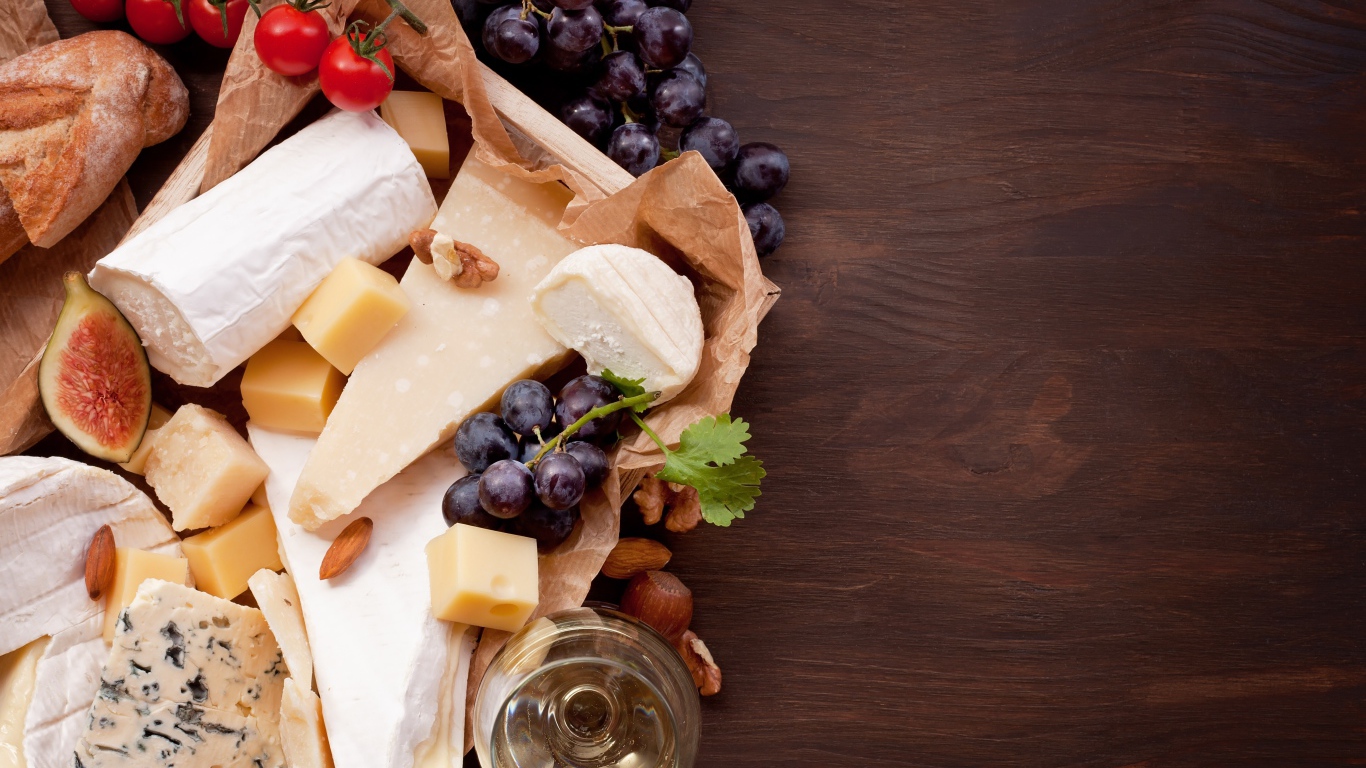 Сыр на столе с виноградом, инжиром и помидорами