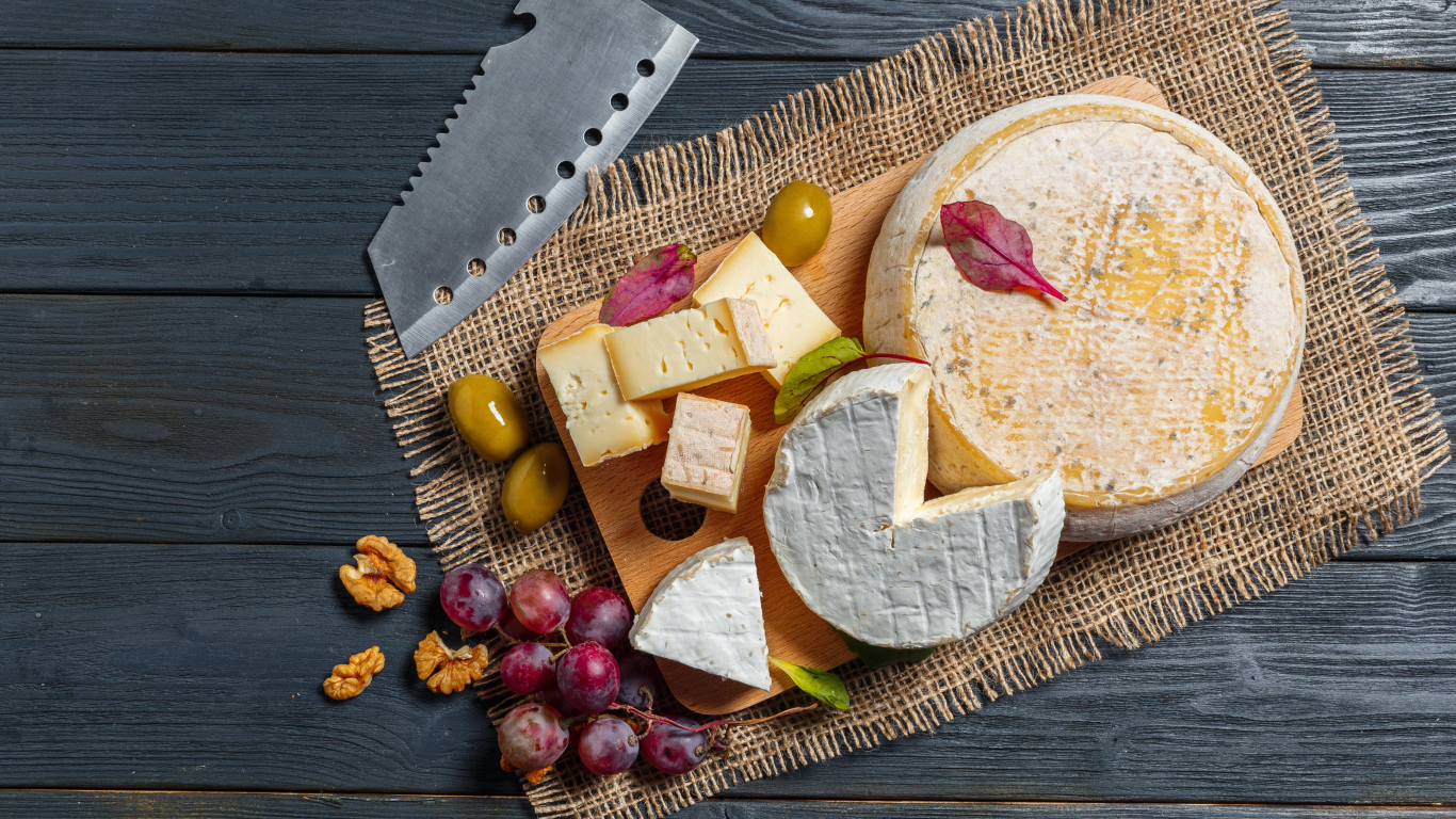 Сыр с плесенью на столе с орехами и виноградом 