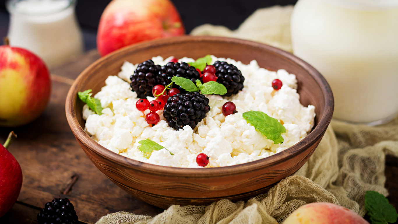 Творог с ягодами в деревянной миске на столе с яблоками
