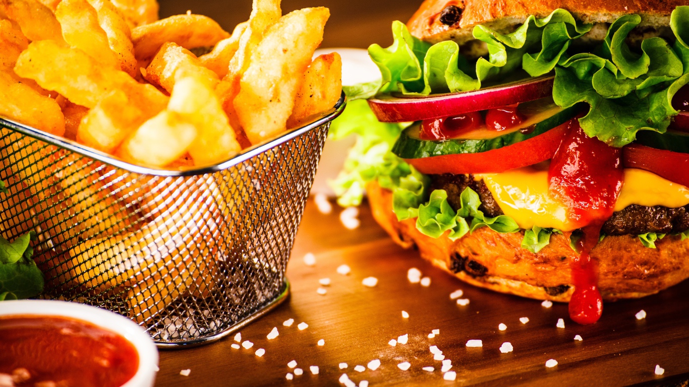 Аппетитный сочный гамбургер на доске с картошкой фри и соусом