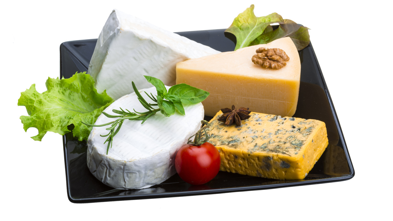 Разные виды сыра на черной тарелке на белом фоне