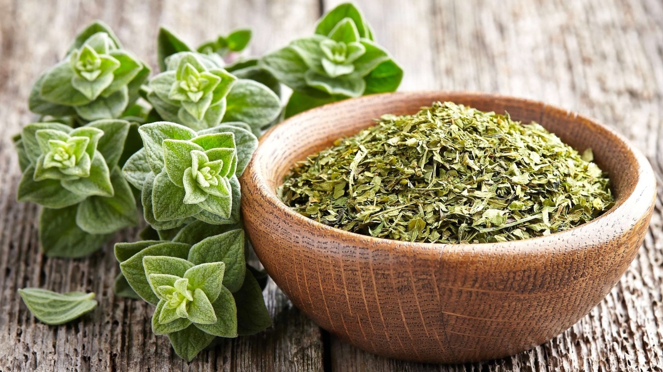 Сухая трава орегано в деревянной миске на столе 