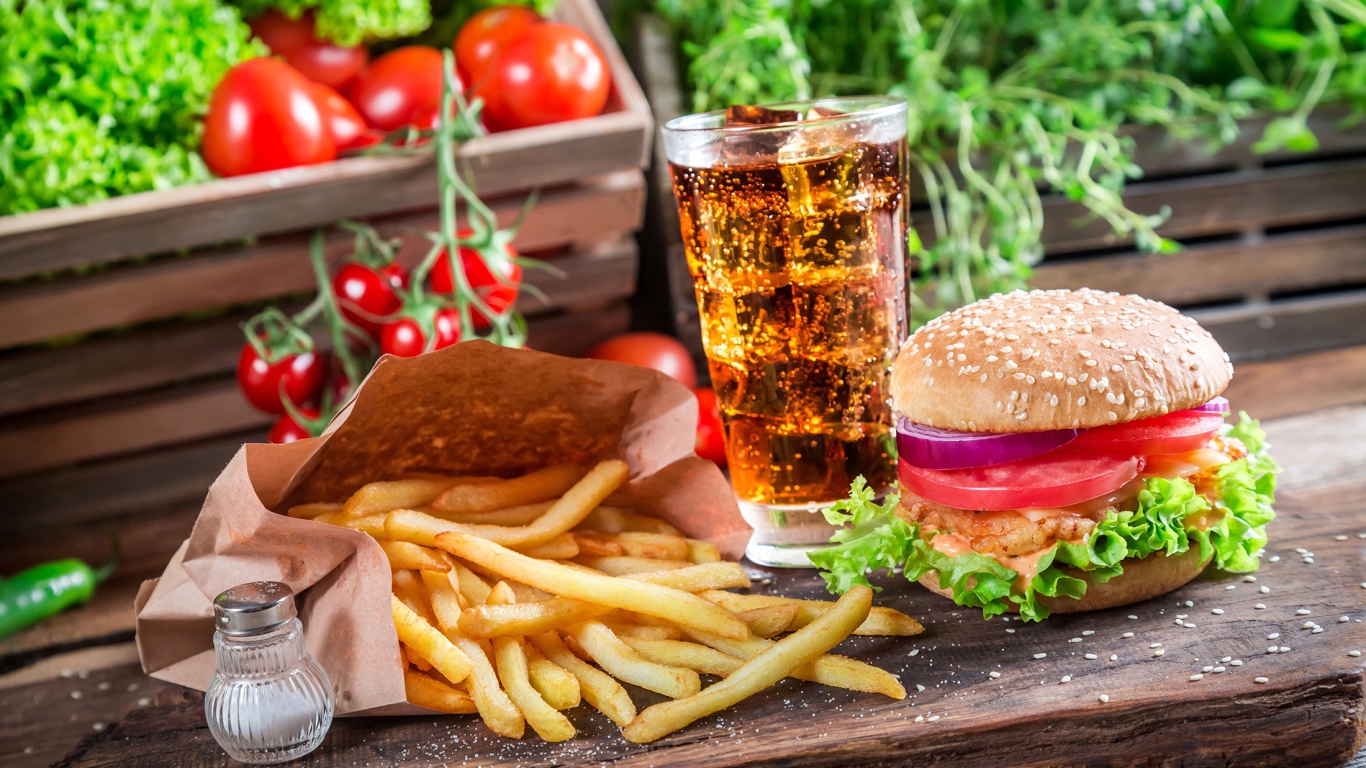 Картофель фри, гамбургер, кола и помидоры на столе