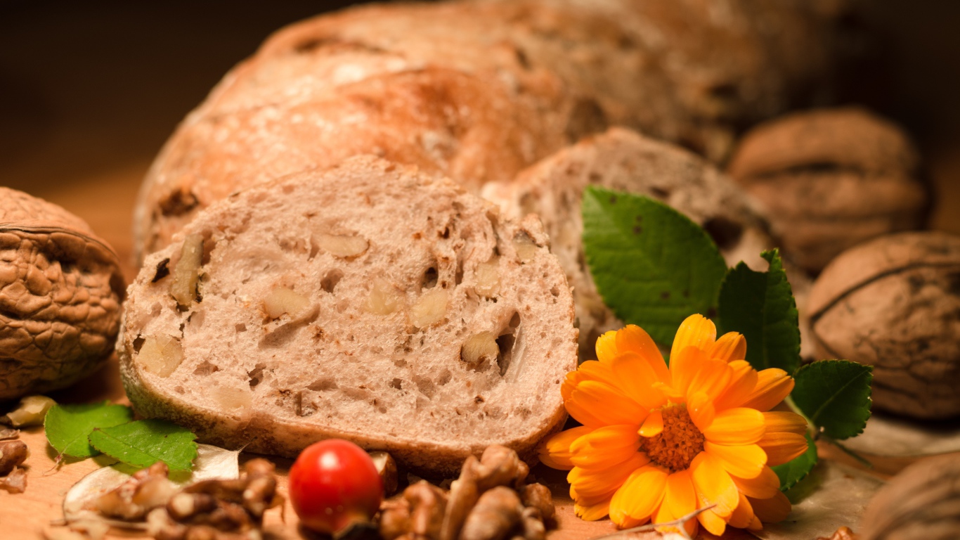 Свежий хлеб с грецкими орехами и цветами календулы на столе