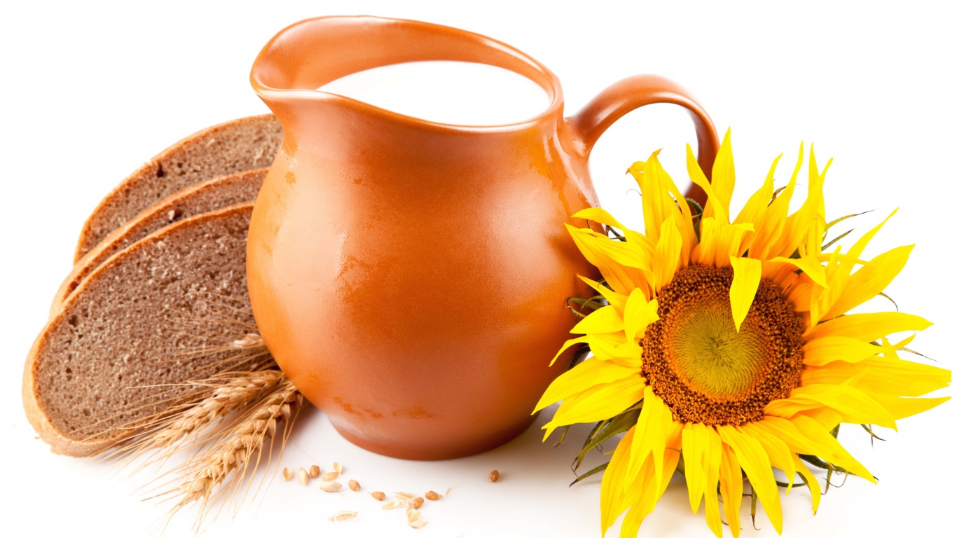 Кувшин с молоком на белом фоне с хлебом и подсолнухом