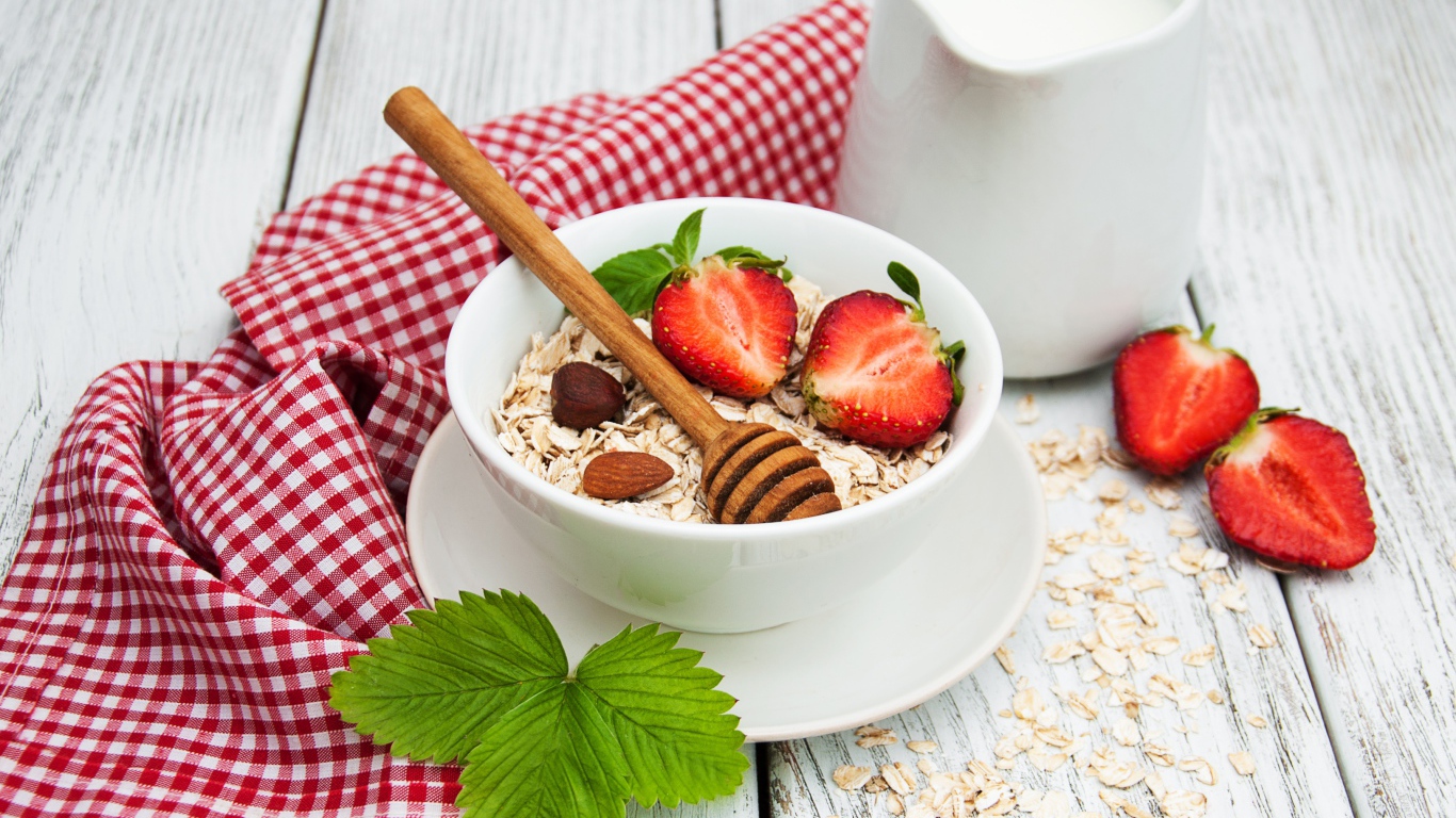 Овсяная каша на столе с молоком и клубникой