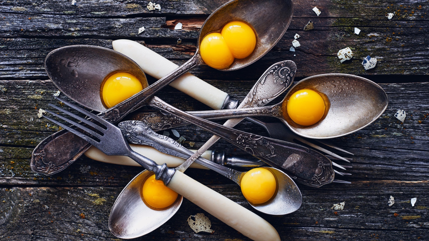 Старые ложки с желтками на деревянном столе