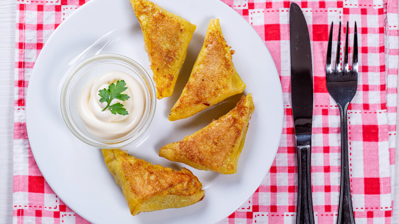 Блинчики со сметаной на столе со столовыми приборами 