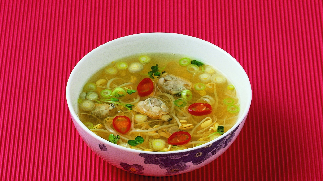 Тарелка супа с морепродуктами на красном фоне