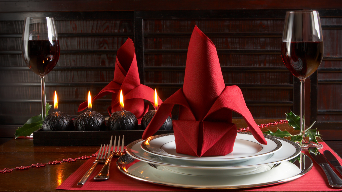 Red napkin on a plate on the table with glasses of wine and candles