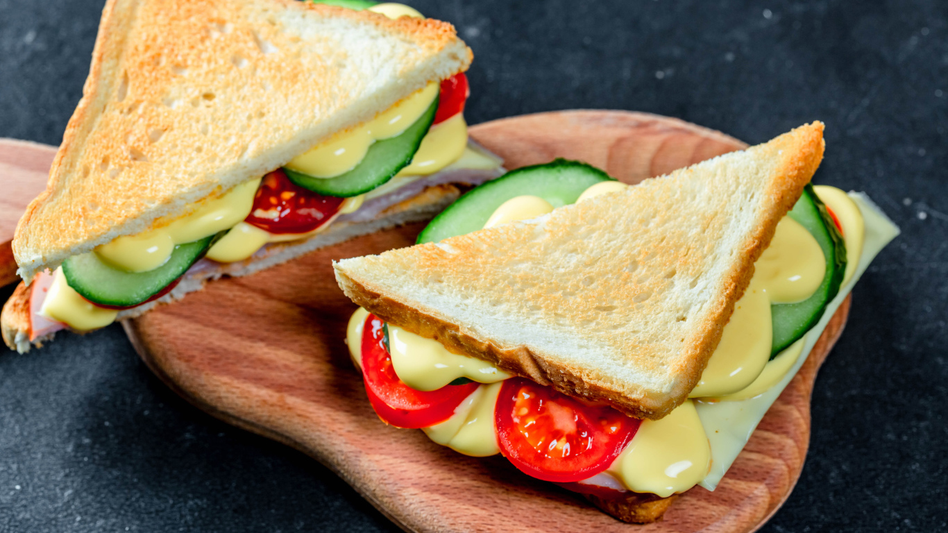 Сэндвич с сыром, помидорами и огурцами на столе