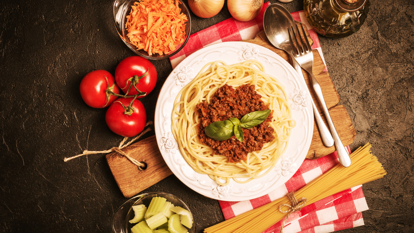 Спагетти с фаршем на столе с овощами