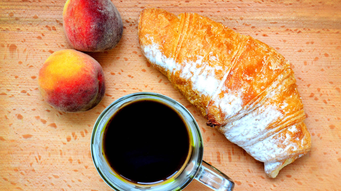 Два персика на столе с кофе и круассаном