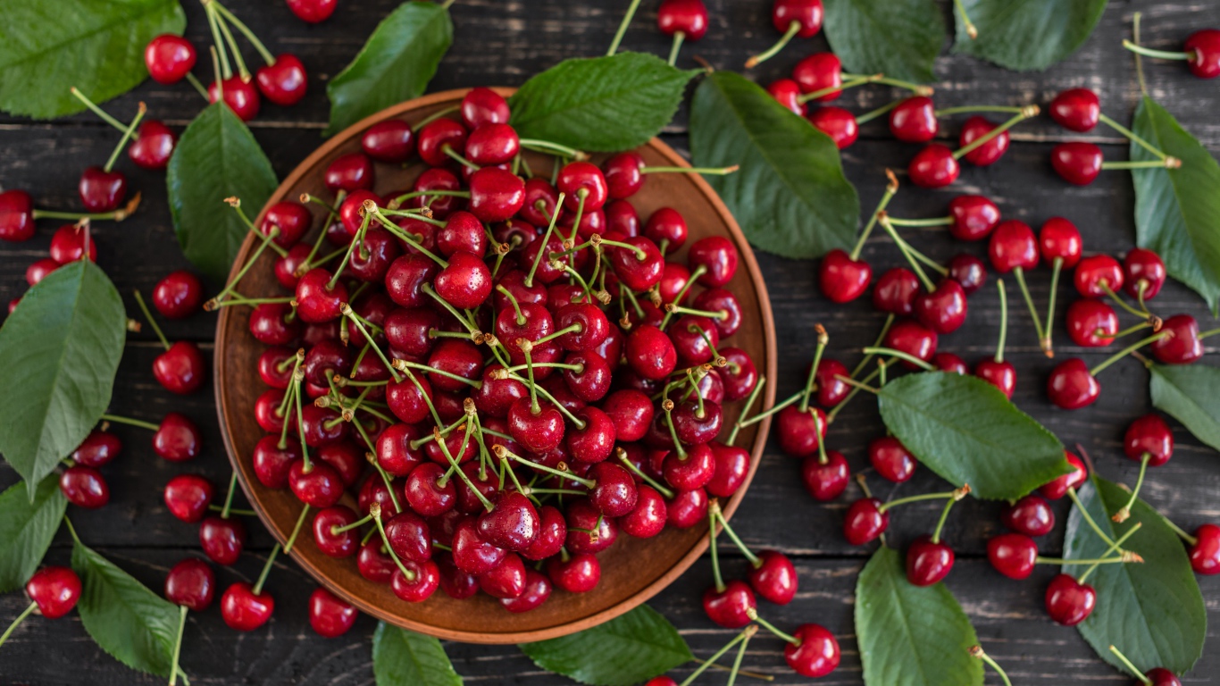 Много спелой красной черешне в миске на столе