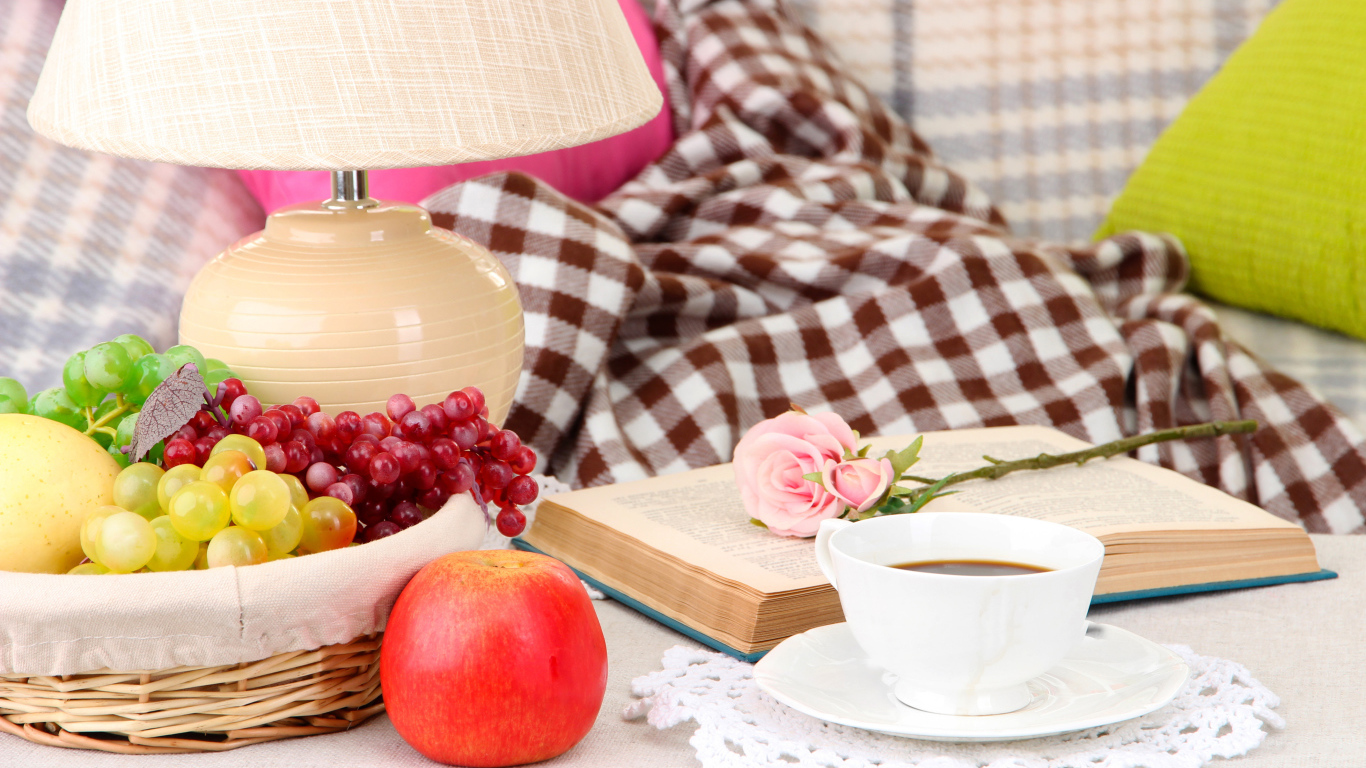 Фрукты в корзине на столе с книгой, чашкой кофе и розой