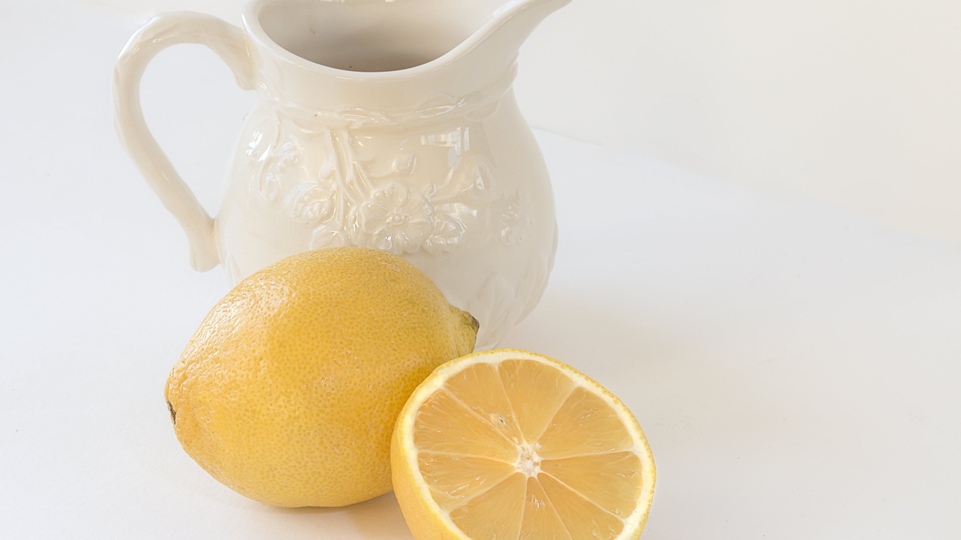 Лимон с белым кувшином на сером фоне