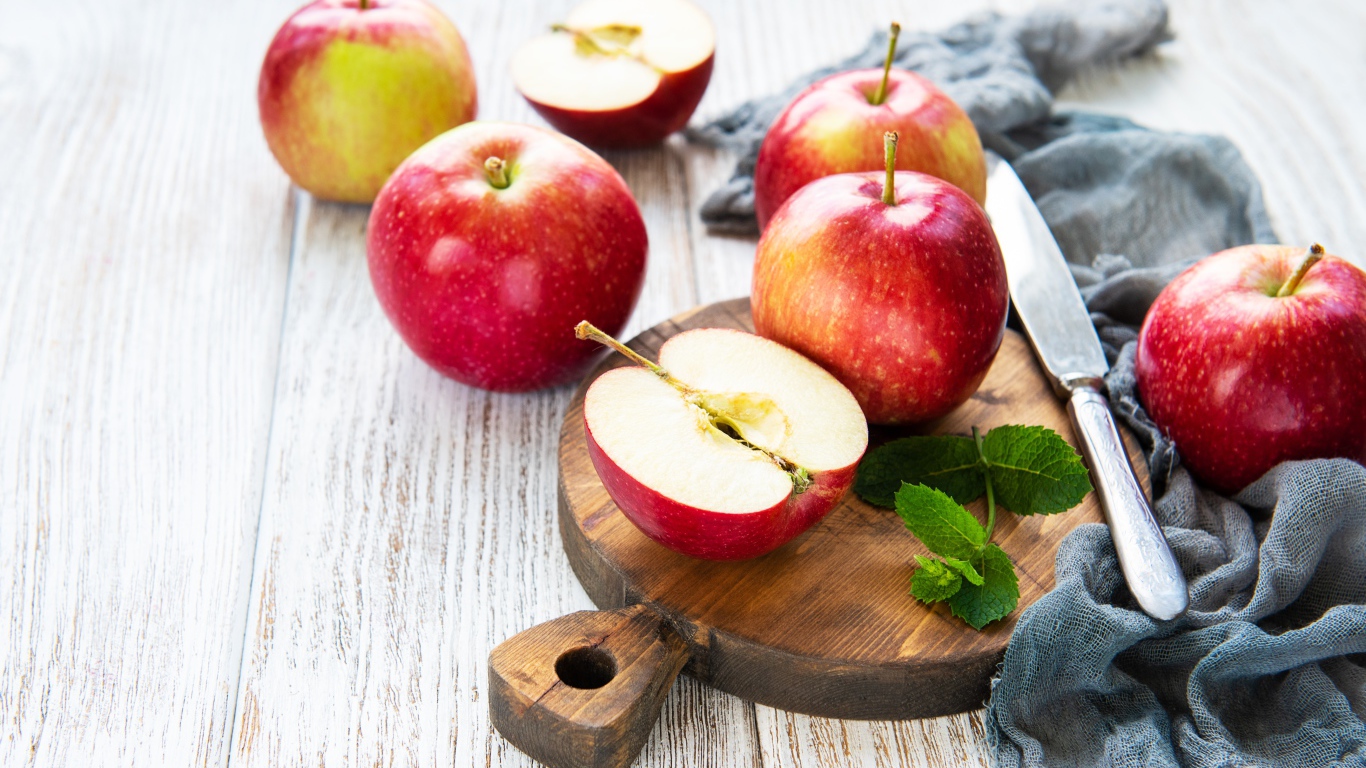 Спелые красные яблоки на разделочной доске с ножом