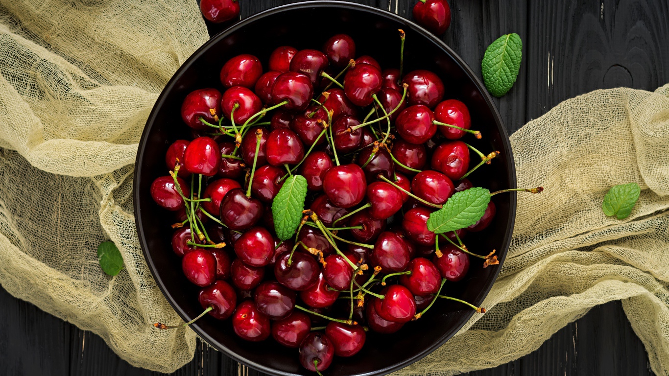 Спелые красные черешни в миске на столе