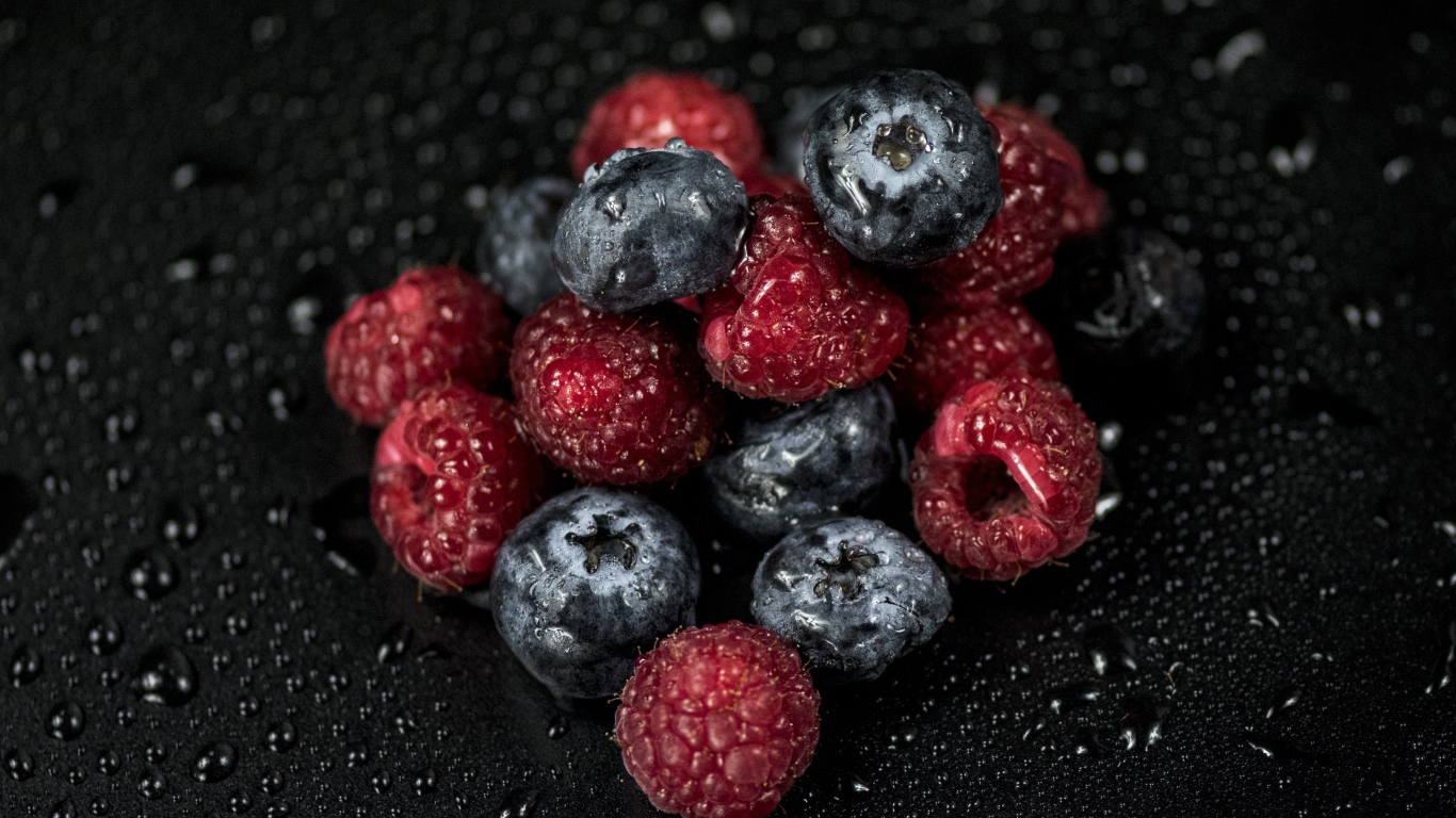 Мокрые ягоды черники и малины на черном фоне