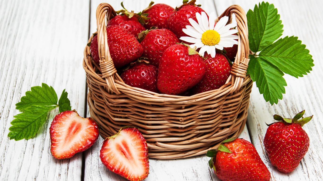 Плетеная корзинка с клубникой, ромашкой и зелеными листьями